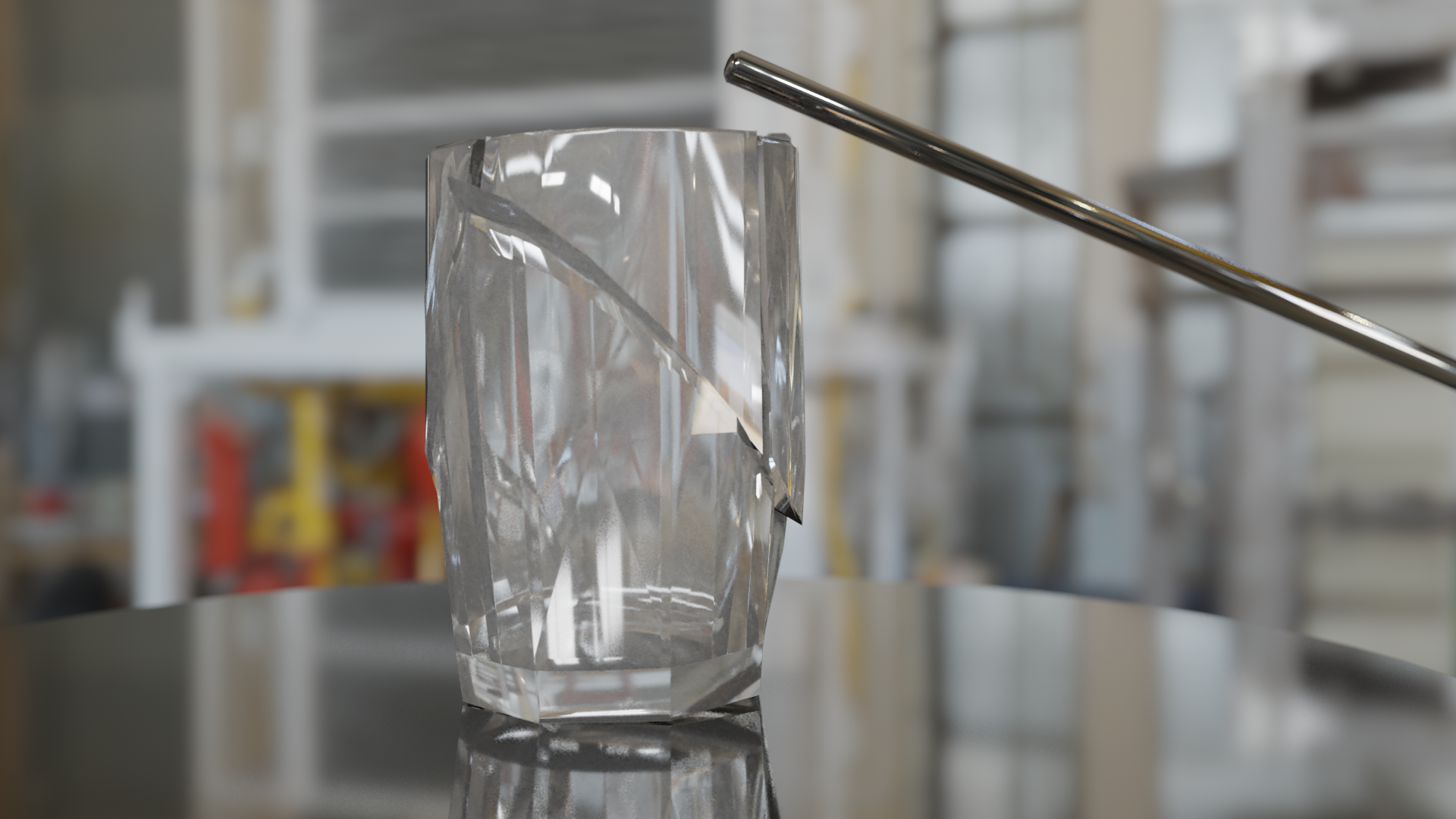 A glass cup on a metal table in a machine shop, with a metal rod slightly above the cup. The glass cup has been broken into several fragments, and it is just starting to fall apart.